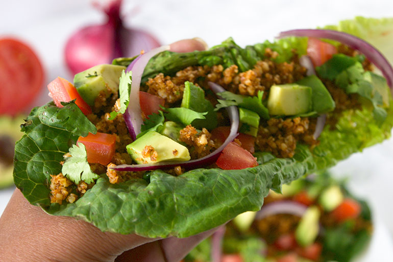 brown. hand holding Raw Walnut Taco Meat lettuce wrap