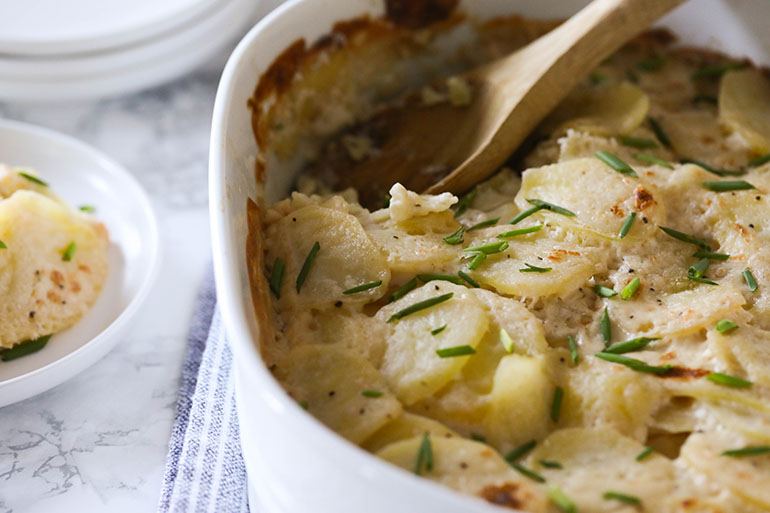 Vegan Scalloped Potatoes with wooden spoon