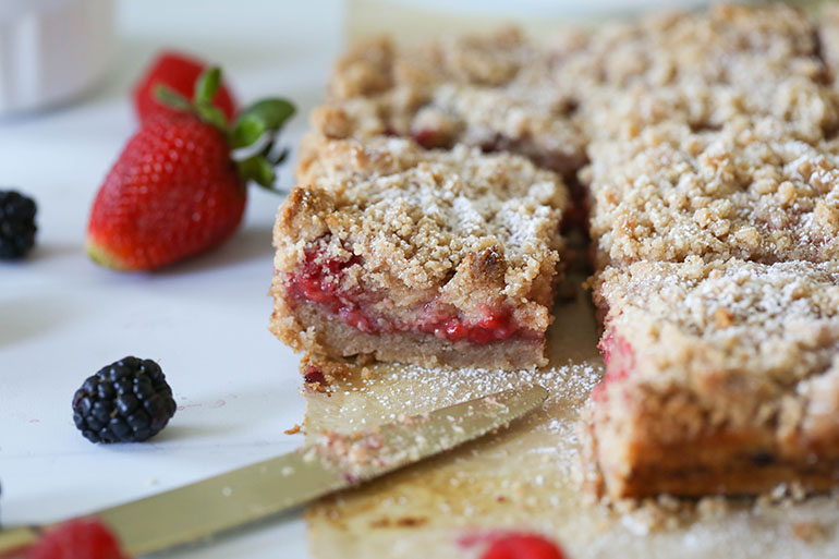 Vegan Triple Berry Crumb Bars on brown parchment paper